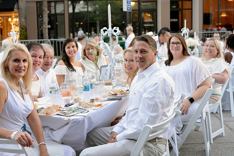 Guests smile at their table Saturday, Aug. 4, 2018, during the 5th annual Piccadilly in White event on East High Street in Jefferson City. Guests wore all white summer attire and enjoyed food and beverages catered by local businesses before getting the chance to win big prizes at a piccadilly-style auction.