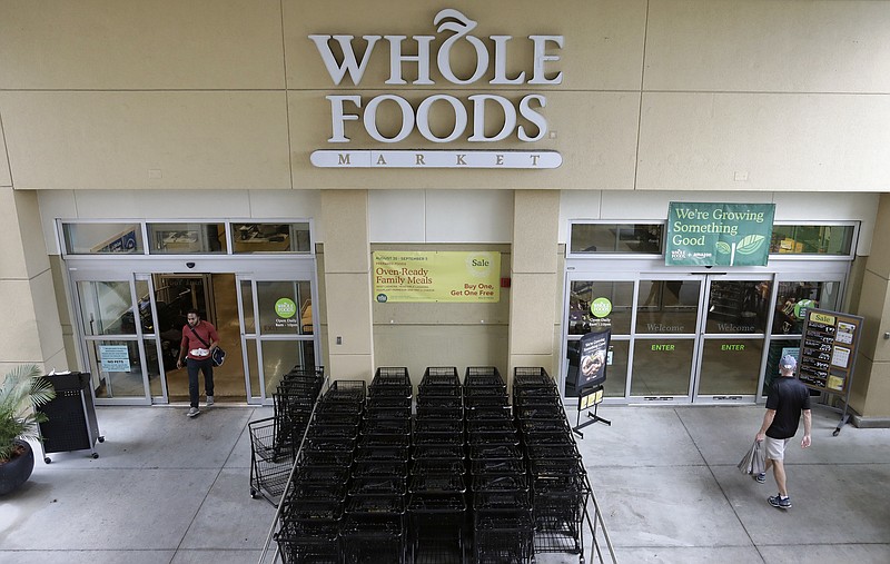 FILE- In this Aug. 28, 2017, file photo, customers shop at a Whole Foods Market in Tampa, Fla. Amazon, known for bringing items to shoppers' homes, is adding a curbside pickup option at Whole Foods for Prime members. The Whole Foods move announced Wednesday, Aug. 8, 2018, is the latest by Seattle-based Amazon.com Inc. since it took control of the grocery chain a year ago. (AP Photo/Chris O'Meara, File)