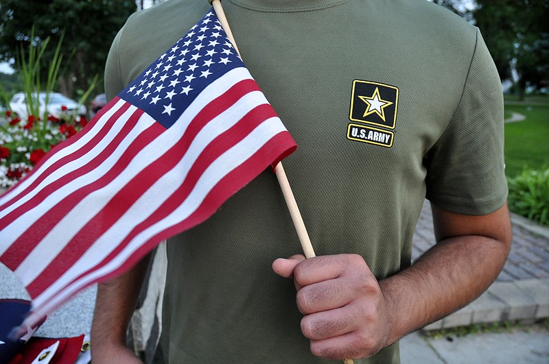 In this July 3, 2018, file photo, a Pakistani recruit, 22, who was recently discharged from the U.S. Army, holds an American flag as he poses for a picture. The U.S. Army has stopped discharging immigrant recruits who enlisted seeking a path to citizenship - at least temporarily.   A memo shared with The Associated Press on Wednesday, Aug. 8 and dated July 20 spells out orders to high-ranking Army officials to stop processing discharges of men and women who enlisted in the special immigrant program, effective immediately.  (AP Photo/Mike Knaak, File)