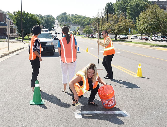 Michelle Funkenbusch uses temporary paint to create a crosswalk pattern. She was one of several participants in Friday's Transportation Summit trying to figure out ways to create safer traffic patterns.