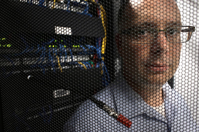 In this Wednesday, Aug. 1, 2018, photo Russell Benoit, of Dartmouth, Mass., marketing manager for AVTECH Software, stands behind the door of a server cabinet in the company's data center in Warren, R.I. AVTECH Software, which makes software to control building environmental issues, is preparing for what some say is the wave of the future: laws requiring businesses to be up-front with customers about how they use personal information. (AP Photo/Steven Senne)