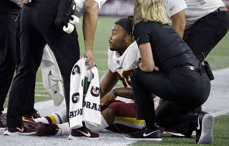 Washington Redskins running back Derrius Guice, center, receives attention on the field after an injury during the first half of a preseason NFL football game against the New England Patriots, Thursday, Aug. 9, 2018, in Foxborough, Mass. (AP Photo/Steven Senne)
