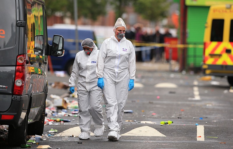 Forensic officers at the scene in the Moss Side area of Manchester, England, where several people have been injured after a shooting, early Sunday Aug. 12, 2018.  Police in Manchester say 10 people have been hospitalized as the result of a shooting after a Caribbean carnival in the city. (Peter Byrne/PA via AP)