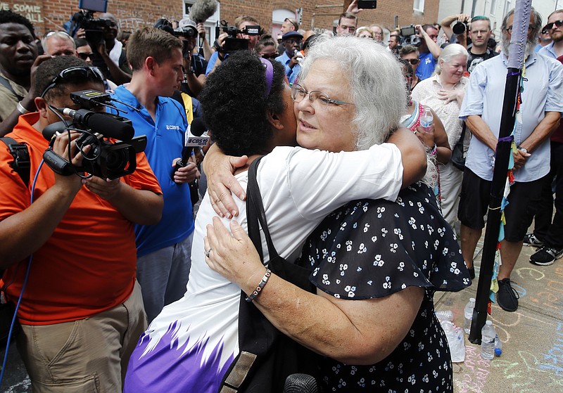 Susan Bro, mother of Heather Heyer who was killed during last year's Unite the Right rally, embraces supporters after laying flowers at the spot her daughter was killed in Charlottesville, Va., Sunday, Aug. 12, 2018. Bro said there's still "so much healing to do." She said the city and the country have a "huge racial problem" and that if it's not fixed, "we'll be right back here in no time." (AP Photo/Steve Helber)