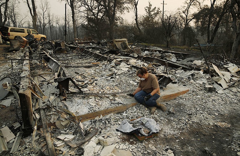Kim Burns sifts through the charred rubble of her home burned in the Carr Fire, Sunday, Aug. 12, 2018, in Redding, Calif. (AP Photo/John Locher)