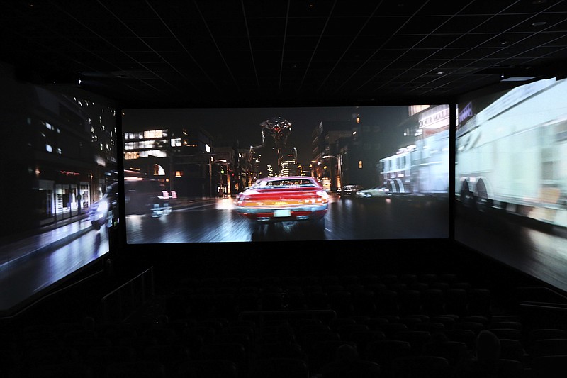 In this photo taken on Thursday, Aug. 9, 2018, a trailer shows a car speeding through traffic as part of a demonstration for ScreenX at Cineworld in London. Sit at the back of the movie theater, and it's possible to see the appeal of ScreenX, the latest attempt to drag film lovers off the sofa and away from Netflix. Instead of one screen, there are three, creating a 270-degree view meant to add to the immersive experience you can’t get from the home TV. (AP Photo/Robert Stevens)