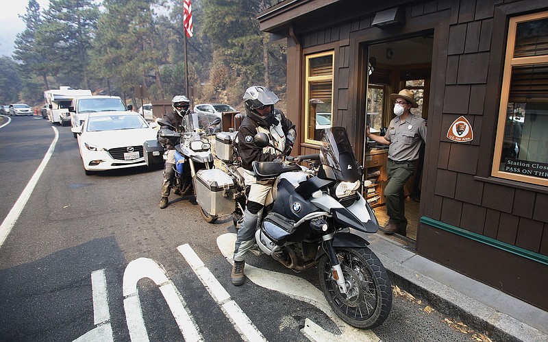 Park Ranger Alex Martinez passes maps out and directs visitors at the Highway 140 gate as Yosemite National Park reopens in California, Tuesday, Aug. 14, 2018. The nearly three-week closure was the result of a wildfire. (AP Photo/Gary Kazanjian)