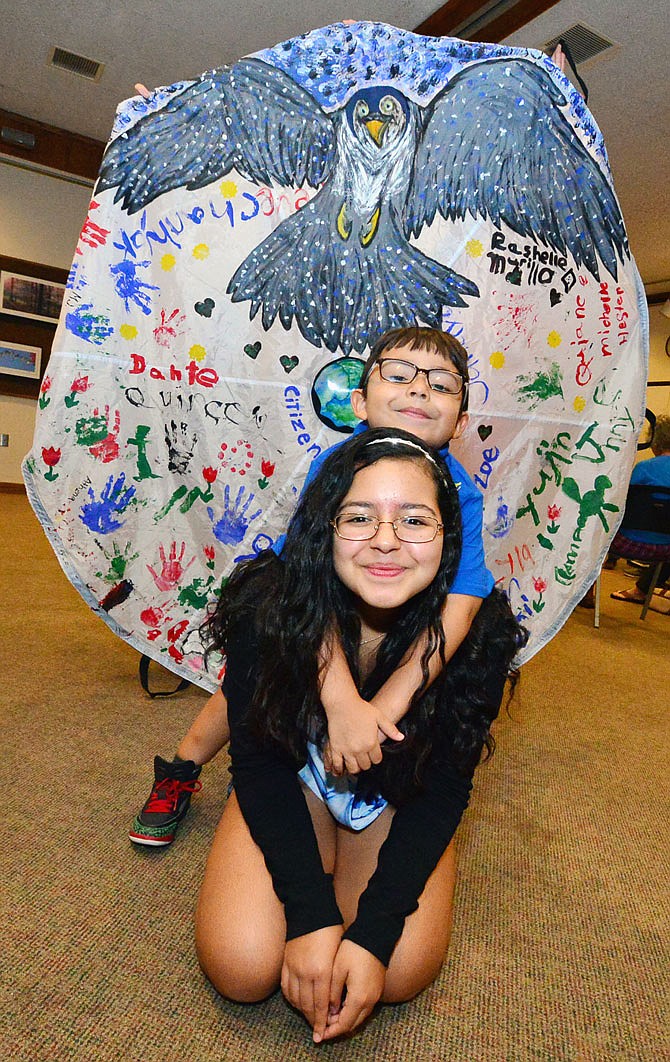 Dante Murillo, 5, and big sister Rashelle, 12, of Jefferson City, pose in front of the parachute they helped create for the Parachutes for the Planet  Mother Earth Project on Wednesday during a Jefferson City Citizens' Climate Lobby meeting at the Missouri River Regional Library. The group planned the project for Earth Day. Groups from 28 countries and 26 states are making parachutes to display on the National Mall in Washington D.C.