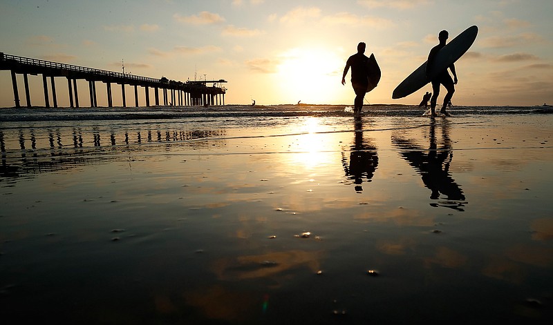 Surfers leave the water next to Scripps Pier Thursday, Aug. 2, 2018, in San Diego. The Scripps Institution of Oceanography says it has recorded the highest sea-surface temperature in San Diego in its 102 years of taking measure. The organization says water at the pier reached 78.6 degrees Fahrenheit (25.9 degrees Celsius) on Wednesday, surpassing a previous high set during an unusually warm period in July 1931. (AP Photo/Gregory Bull)