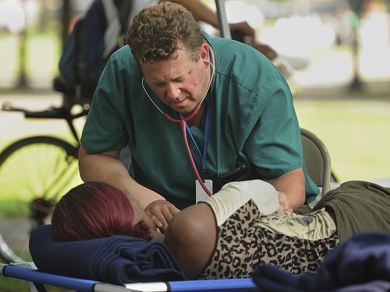 One of three simultaneous drug overdose victims is treated on the New Haven Green, a city park in New Haven, Conn., Thursday, Aug. 16, 2018. Investigators try to determine exactly what sickened the victims. People started falling ill Wednesday morning, mostly on the New Haven Green. No deaths were reported. Police have arrested a man who they say may have passed out free samples of synthetic marijuana. (Brian A. Pounds/Hearst Connecticut Media via AP)