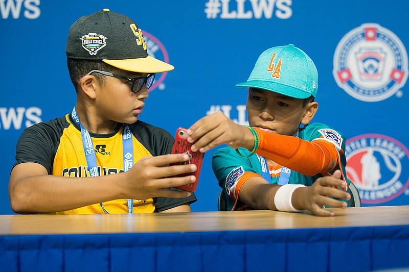 In this photo provided by Georgianna DeCarmine, Georgia shortstop Tai Peete, left, uses Google Translate on his phone to communicate with Panama outfielder Rolando Rodriguez during an interview at the Little League World Series in South Williamsport, Pa., Tuesday, Aug. 14, 2018. (Georgianna DeCarmine via AP)