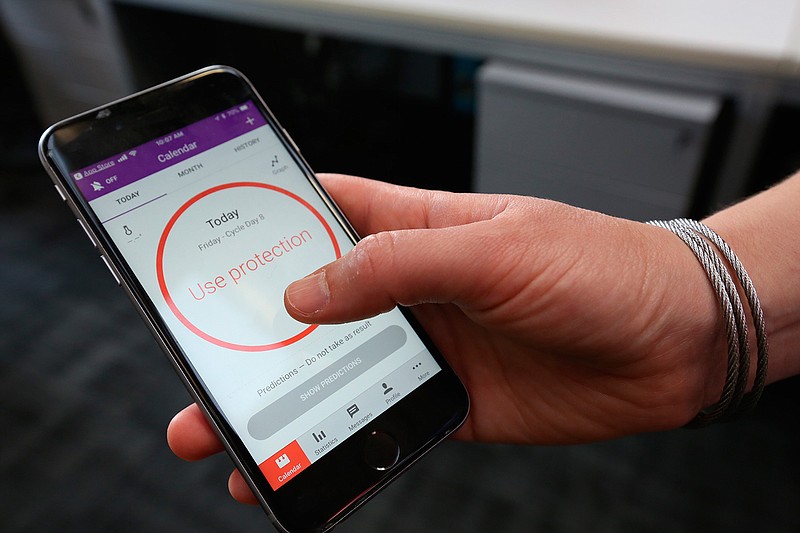 A women demonstrates using the Natural Cycles smartphone app,  in London, Friday, Aug. 17, 2018.  The mobile fertility app, has become the first ever digital contraceptive device to win FDA (US Food and Drug Administration) marketing approval, enabling women to track their menstrual cycle and uses an algorithm to determine when they're fertile, and need to use birth control protection. (AP Photo/Nishat Ahmed)