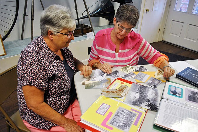 Janet Koetting, left, and Judy Hoelscher look at photos of boats along the Osage Bend area of the Osage River from the Veit family, as they go over information they will present at the "Getting to Know Your Communities" 2018 series finale about Osage Bend, part 2 (the Osage River), at 7 p.m. Tuesday at St. Margaret of Antioch Catholic Church Hall.