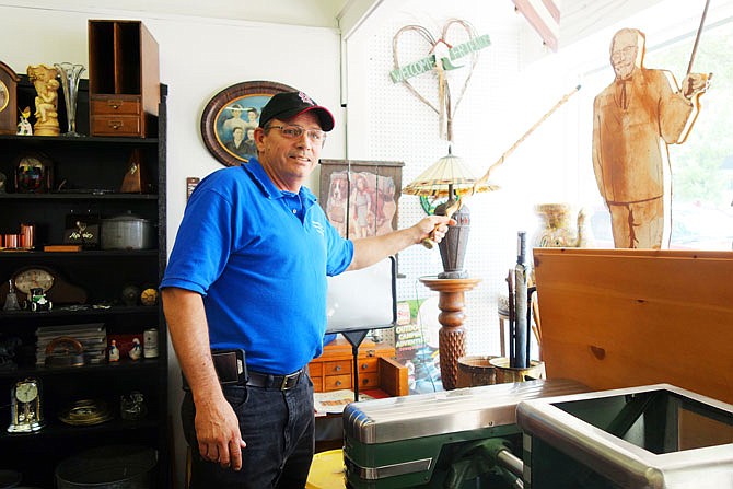 Brian Webb, co-owner of the newly opened Charlotte Web's Attic, points out one of his favorite items in the shop. Old Kentucky Fried Chicken signs like this one are rare, especially in good condition, he said. He and wife Tammy Webb's store is one of two new antique stores coming to downtown.