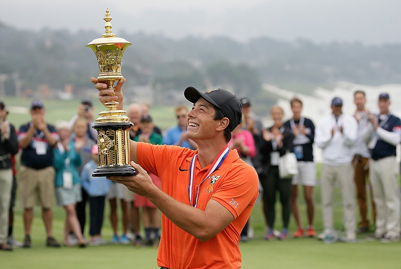 Viktor Hovland holds up the Havemeyer Trophy on the 13th green of the Pebble Beach Golf Links after winning the USGA Amateur Golf Championship on Sunday in Pebble Beach, Calif. Hovland became the first Norwegian to win the U.S. Amateur, beating UCLA sophomore Devon Bling 6 and 5 to cap a dominant week at Pebble Beach. 