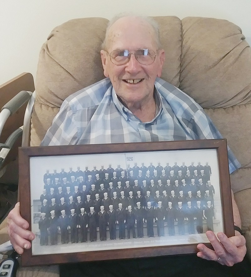 Bernard Heet holds the photograph of his U.S. Navy boot camp graduation class in January 1945 at Farragut, Idaho. The sailor later trained as a signalman and served during WWII aboard a submarine chaser throughout the Pacific Ocean.