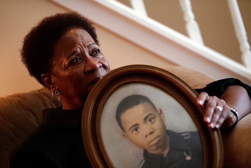 In this Aug. 9, 2018 photo, Eberlene King poses with a photograph of her brother William Roy Prather when he was about 15-years-old at her home in Doraville, Ga. Prather was shot in the face on Halloween night 1959 in Corinth, Miss., and died the next day. (AP Photo/John Bazemore)