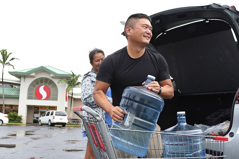 Loren, right, and Ruby Aquino, of Honolulu, load water into their car ahead of Hurricane Lane, Wednesday, Aug. 22, 2018 in Honolulu. Hurricane Lane has weakened as it approaches Hawaii but was still expected to pack a wallop, forecasters said Wednesday. The National Weather Service said tropical-storm-force winds could begin as early as Wednesday afternoon on the Big Island. (AP Photo/Caleb Jones)