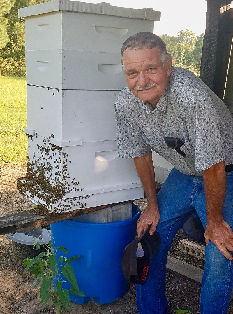 Local beekeeper Sidney Brown poses with his beehive.