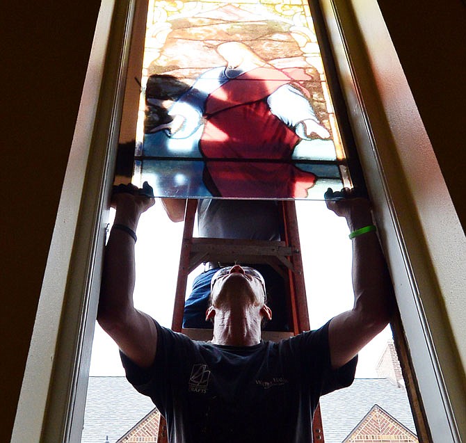 Joe Martinez,on ladder, installs temporary plexiglass windows with a stained glass window appliqué as David Crow steadies Saturday morning at First United Methodist Church. The original windows have been removed to be repaired so the temporary windows will be in place for that time. The two work for Willet Hauser & Associated Crafts.