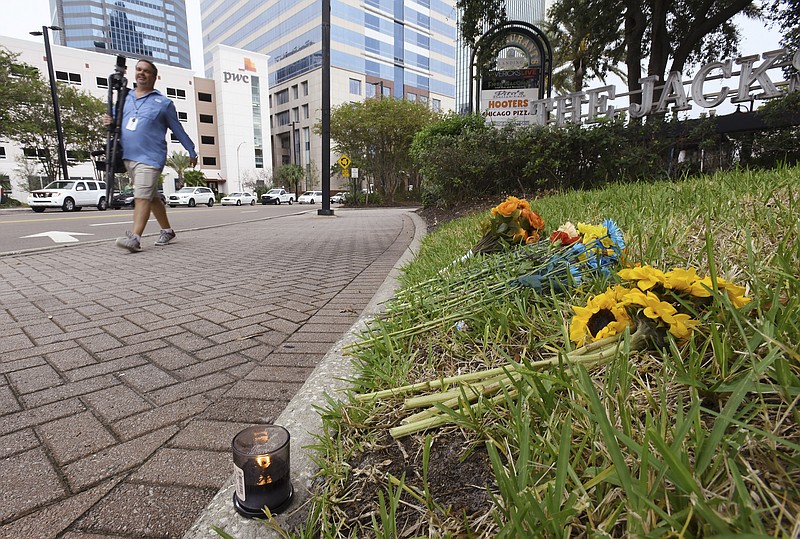 A single candle and a few flowers were left on the grass outside the Jacksonville Landing Tuesday, Aug. 28, 2018, as the facility prepared to reopen after Sunday's mass shooting there Sunday during a Madden Championship Series video game competition at the Good Luck Have Fun video game bar inside Chicago Pizza. The shooter David Katz from Baltimore, MD left three people dead, including himself and many more wounded in the crowded competition space. (Bob Self/The Florida Times-Union via AP)