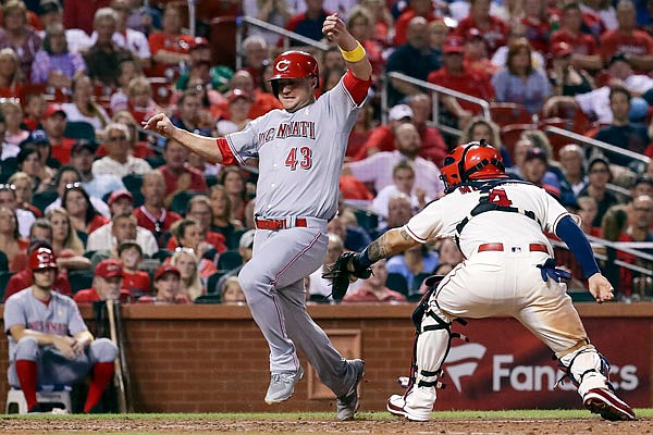 Scott Schebler of the Reds avoids the tag of Cardinals catcher Yadier Molina to score a run during the seventh inning of Saturday night's game at Busch Stadium.