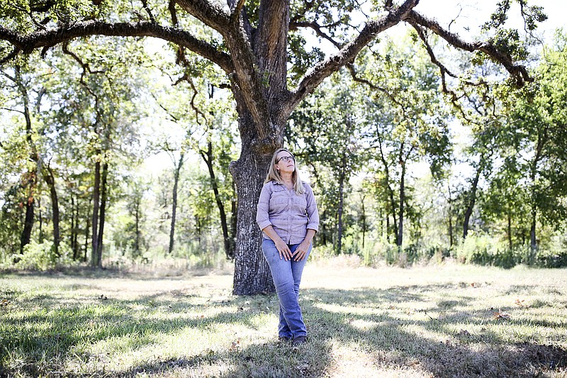 In this Aug. 30, 2018, photo Carolyn White, conservation director for the Memorial Park Conservancy, stands by a stressed Post Oak Tree at the park in Houston. (Elizabeth Conley/Houston Chronicle via AP)