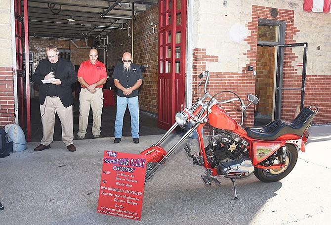  Trinity Lutheran Pastor Sam Powell, left, stands in the garage bay doorway at the Jefferson City Fire Museum as he asks for a blessing over the motorcycle in the foreground and those it was made to honor. He's joined by Steve Holtmeier, president of the museum, middle, and bike donor Woody West. The motorcycle is a 1980 Harley Davidson Ironhead Sportster customized by West. Several area firefighters were joined by city dignitaries and members of the Patriot Guard and American Legion Riders and others Tuesday morning at the museum for the presentation of The Remember Rally Chopper.