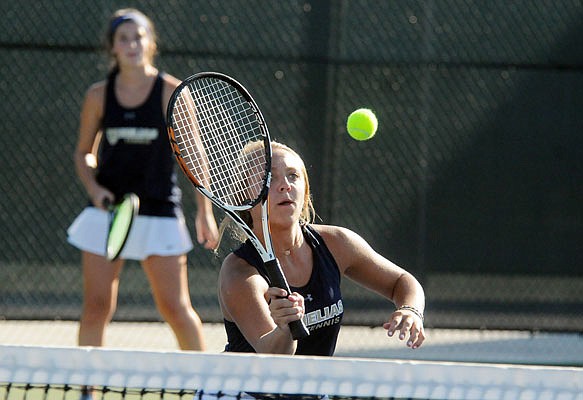 Mya Bremer makes a return while Helias teammate Catherine Conley of Helias watches during their doubles match Thursday against Hickman at the Crusader Athletic Complex.