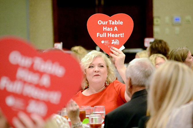 Kim Quinn, a survivor of congestive heart failure, holds up a donation sign Friday during the Go Red for Women Luncheon. 