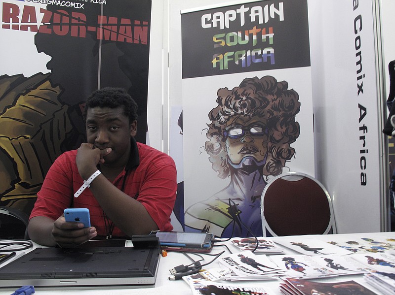 In this Saturday, Sept. 15, 2018 photo, Bill Masuku, a Zimbabwean comic book artist and writer, sits at a stall at Comic Con Africa, a three-day comic book and pop culture convention in Johannesburg, South Africa. The success of Marvel's "Black Panther" film spiked interest in African stories, and creators on the continent hope to capitalize with more comic book characters of their own. The three-day convention ending Sunday in South Africa was a platform for their efforts, even if it was dominated by the global superheroes, villains and other pop culture figures who have been around for decades. (AP photo/Christopher Torchia)