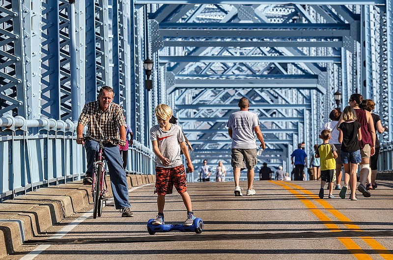 Grant Hagan, 8, rides a hoverboard across the Glover Cary Bridge as his grandfather Donnie Hagan follows on a bicycle during Bridge Day, Saturday, Sept. 15, 2018 in Owensboro, Ky.   (Greg Eans/The Messenger-Inquirer via AP)