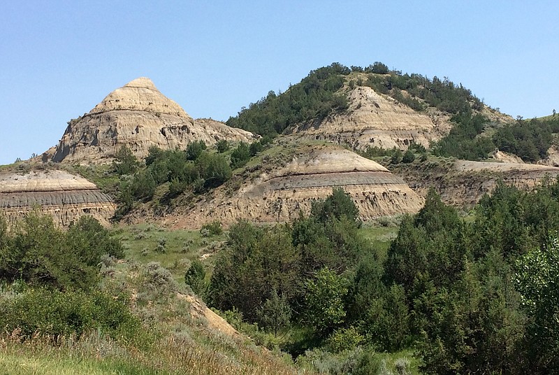 In this July 5, 2018, photo, eroded hills are shown in Theodore Roosevelt National Park in western North Dakota. North Dakota's Public Service Commission on Monday, Sept. 17, 2018, discussed an administrative law judge's recommendation that the regulators dismiss a challenge to the location of an oil refinery being developed near Theodore Roosevelt National Park. One commissioner indicated she'll likely vote to heed the advice, while the other two members didn't immediately indicate their position. Meridian Energy Group plans to build the $800 million Davis Refinery 3 miles from the park. (AP Photo/Blake Nicholson)