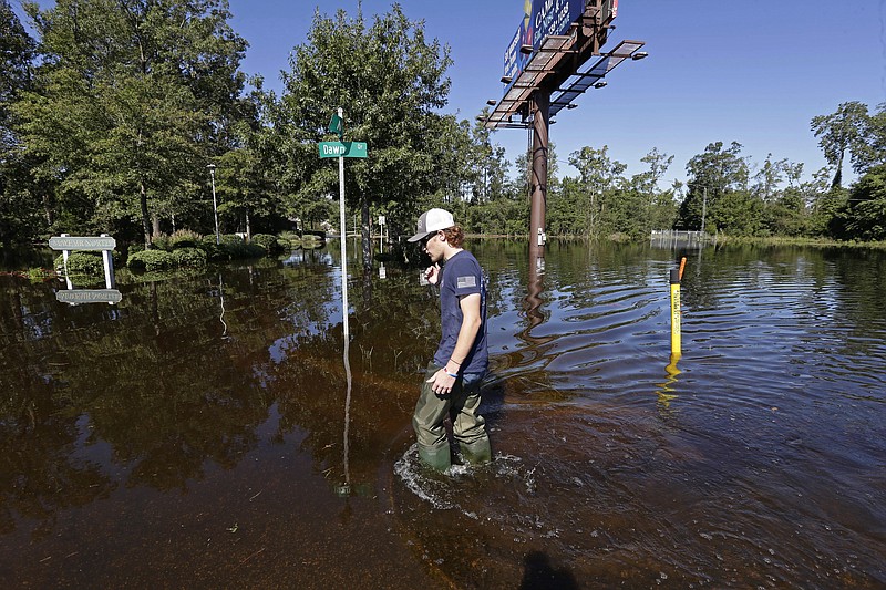 Zachary Conner wades into a flooded neighborhood to check on his girlfriend in Lumberton, N.C., Tuesday, Sept. 18, 2018, following the effects from Hurricane Florence. (AP Photo/Gerry Broome)