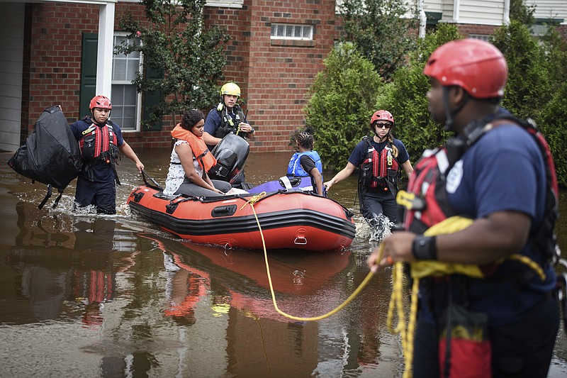 Emergency personnel take a family to safety after Little River overflowed its banks and flooded part of the apartment complex on Monday, Sept. 17, 2018, in Spring Lake, N.C. North Carolina Gov. Roy Cooper warned that the flooding set off by rain from Florence is far from over and will get worse in places.  (Andrew Craft/The Fayetteville Observer via AP)