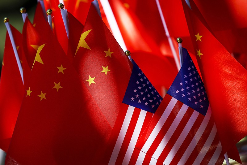 In this Sept. 16, 2018, photo, American flags are displayed together with Chinese flags on top of a trishaw in Beijing. The American Chamber of Commerce in China says Beijing will "dig its heels in" after U.S. tariff hikes and appealed for a negotiated end to their trade battle. The chamber on Tuesday, Sept. 18 warned a "downward spiral" appears certain after President Donald Trump approved a tariff hike on $200 billion of Chinese imports in a dispute over Beijing's technology policy. (AP Photo/Andy Wong)
