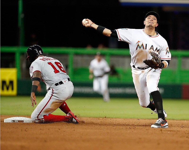 Miami Marlins shortstop Miguel Rojas throws to first to attempt a double play after getting Washington Nationals' Victor Robles (16) out at second during the seventh inning Monday in Miami. Trea Turner was safe at first and Adam Eaton scored on the play.