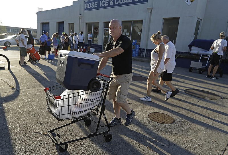 Kyle Crawford uses a shopping cart to carry bags of ice he purchased days after Hurricane Florence in Wilmington, N.C. Wednesday, Sept. 19, 2018. (AP Photo/Chuck Burton)