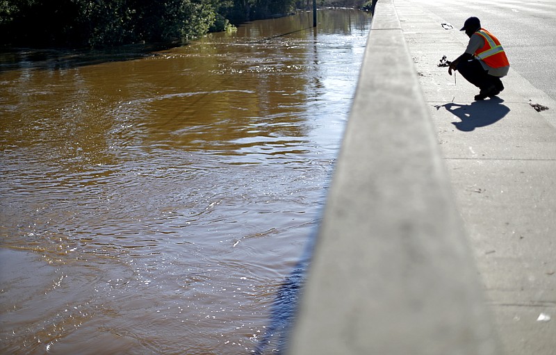 Maine Johnson with the city's communications department, takes photos of the Cape Fear River after its projected time of cresting in Fayetteville, N.C., Wednesday, Sept. 19, 2018. (AP Photo/David Goldman)