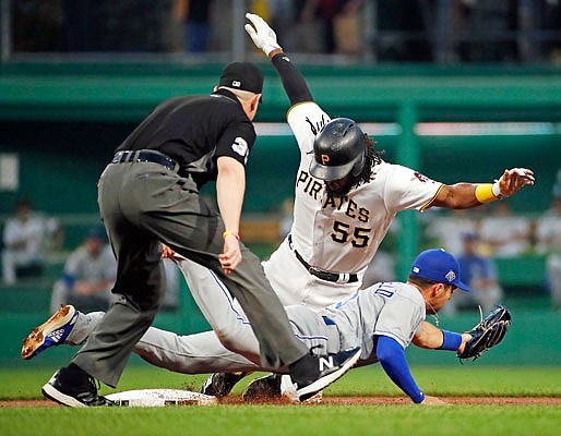 Josh Bell of the Pirates slides safely into second with a double around the tag of Royals second baseman Whit Merrifield with umpire Carlos Torres making the call during Tuesday night's game in Pittsburgh.