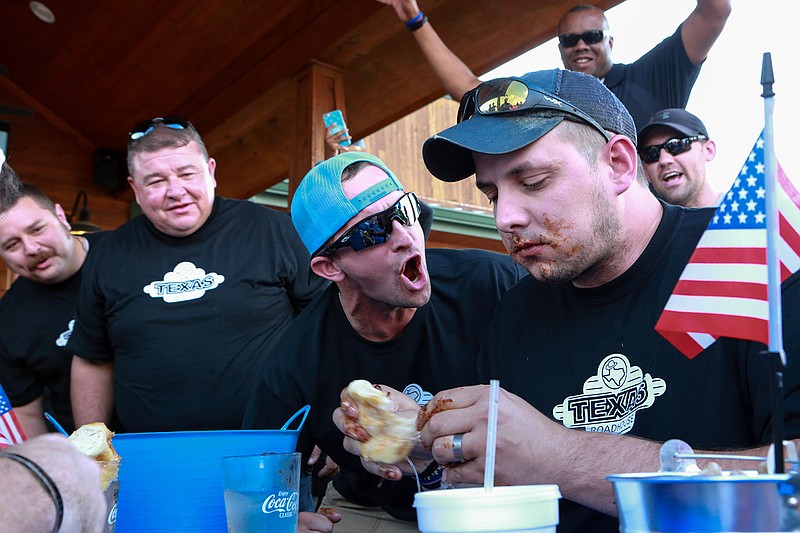 Kris Smith from the Texarkana, Texas, Police Department eats ribs while being cheered on by his teammates at the Texas Roadhouse rib-eating challenge against the Arkansas Fire Department on Thursday in Texarkana, Texas. The event was open to the public for everyone to see who could eat ribs the fastest and the restaurant donated 10 percent of the night's proceeds to the winning team's favorite charity.