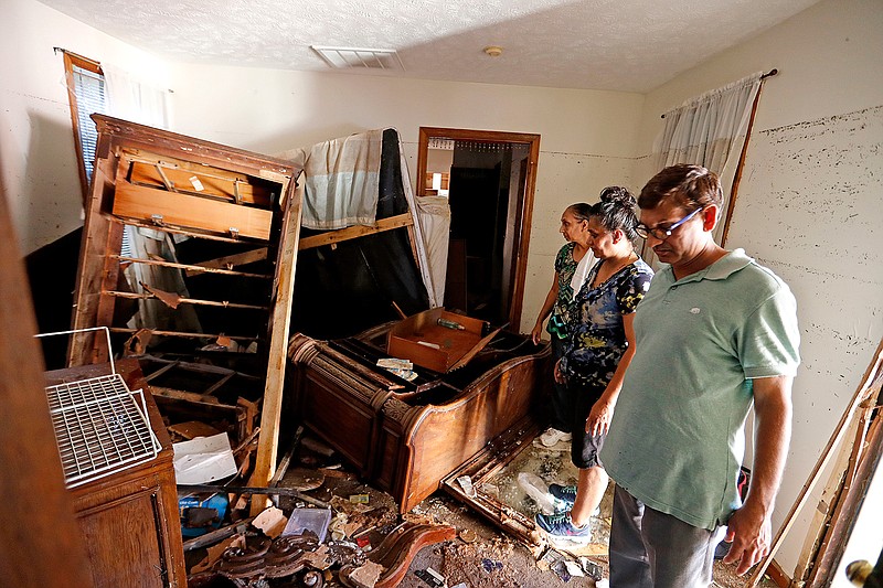 In this Wednesday, Sept. 19, 2018 photo, Smita Depani, center, stands in the apartment she lived in while surveying the damage with her brother-in-law Jayanti Depani, right, and sister-in-law Puspa Manvar in the Starlite Motel they own which was destroyed in the flooding from Hurricane Florence in Spring Lake, N.C. (AP Photo/David Goldman)