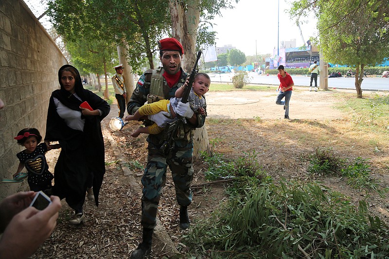 In this photo provided by Mehr News Agency, an Iranian army member carries away a child from a shooting scene during a military parade marking the 38th anniversary of Iraq's 1980 invasion of Iran, in the southwestern city of Ahvaz, Iran, Saturday, Sept. 22, 2018. Gunmen attacked the military parade, killing at least eight members of the elite Revolutionary Guard and wounding 20 others, state media said. (AP Photo/Mehr News Agency, Mehdi Pedramkhoo)