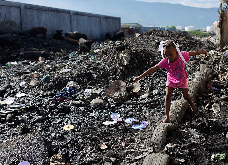In this Nov. 21, 2017, file photo a girl returns from a designated area where neighbors use the bathroom outside, in the Cite Soleil slum of Port-au-Prince, Haiti. Global poverty has fallen to a record low. The World Bank says 10 percent of the world's population lived on less than $1.90 a day in 2015, down from 11.2 percent in 2013. That means 735.9 million people lived below the poverty threshold in 2015, down from 804.2 million. (AP Photo/Dieu Nalio Chery, File)