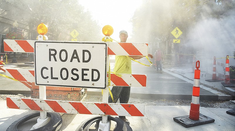 In this September 2018 photo, Chris Reider wraps yellow tape around barricades on Madison Street in an effort to keep traffic off of the newly-poured concrete. Reider worked for Sam Gaines Construction as it worked on High Street and Madison Street.