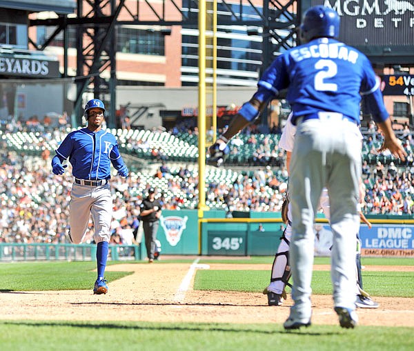 Alcides Escobar (right) waits to congratulate Royals teammate Rosell Herrera after both scored on a single by Cam Gallagher during the sixth inning of Sunday afternoon's game against the Tigers in Detroit.