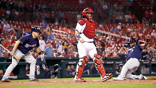 Eric Thames of the Brewers scores past Cardinals catcher Yadier Molina as teammate Erik Kratz watches during the eighth inning of Monday night's game at Busch Stadium.