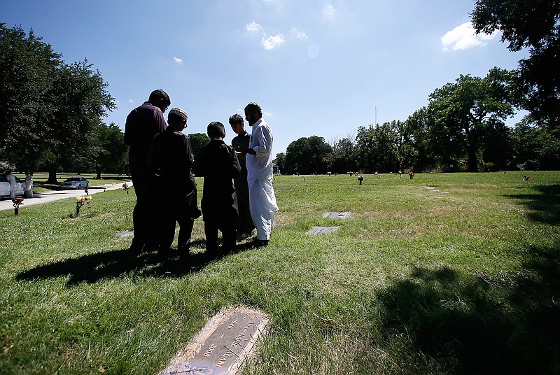In this July 17, 2015, file photo, a family gathers in prayer as they visit a family member buried in the Islamic Garden at Restland Cemetery in Dallas. Leaders of a rural Texas town have approved design plans for a Muslim cemetery three years after the project was first met with derision and claims that it was a precursor to a Muslim training center. The city council in Farmersville on Thursday, Sept. 20, 2018, OK'd the cemetery plans submitted by the Islamic Association of Collin County. (AP Photo/Tony Gutierrez, File)