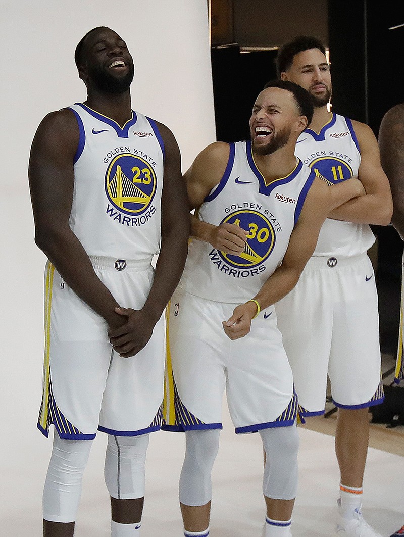 Golden State Warriors' Stephen Curry, center, laughs between Draymond Green, left, and Klay Thompson as they pose for photos for the team's photographer during media day at the NBA basketball team's practice facility in Oakland, Calif., Monday, Sept. 24, 2018. (AP Photo/Jeff Chiu)