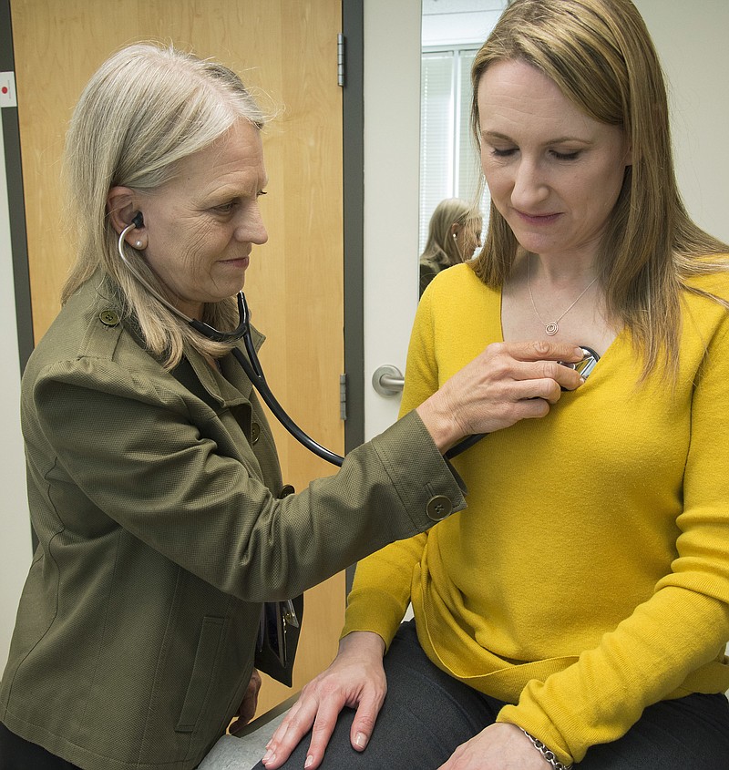 In this 2016 photo provided by the University of Washington, Dr. Linda Vorvick examines Heather VanDusen at UW Neighborhood Clinic in Seattle. When emergency tests showed the telltale right-sided pain in VanDusen's abdomen was appendicitis, she figured she'd be quickly wheeled into surgery. But doctors offered her the option of antibiotics instead. (Clare McLean/UW Medicine via AP)